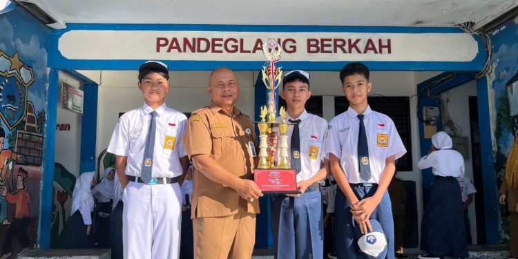 Kepala SMP Negeri 1 Pandeglang Ruli Purnama berfoto bersama siswa juara 1 lomba ensamble FL3SN 2026 Zefanya Sotar Duga di halaman sekolahnya, Senin, 18 Mei 2026.